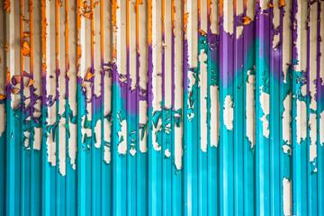 Colorful background of turquoise puple and orange vertical stripes - interesting peeling paint on corregated metal wall