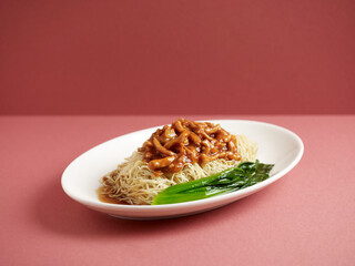 Spicy Minced meat Noodle in a bowl with soup, chili sauce and spring onion top view on wooden table