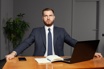 Serious pensive thoughtful focused young businessman in office with laptop