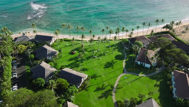 4K Aerial drone shot of Poipu village Beach coastline in Kauai island, Hawaii with teal blue Pacific Ocean with waves coming in on sandy beach with nice houses with ocean views. USA travel background