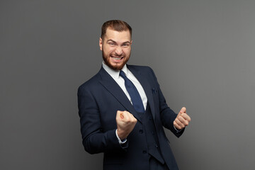 Happy excited businessman laughing against grey studio wall background portrait. Business win, fun and success concept