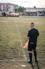 Referee observing the development of a soccer game in a soccer field during a sunset