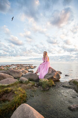 Woman in a long pink dress on the beach, sunset