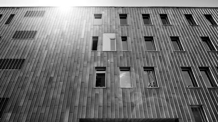 Fragment of modern urban geometry. Walls  office building made of steel and glass. Bright sunny day with sunbeams on the sky. Black and white.