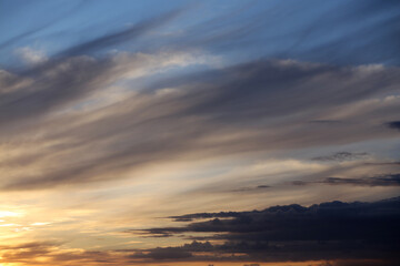Fototapeta premium Light and dark layered clouds in the summer sky at sunset.