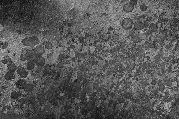 Old dark gray wall with black spots. Textured natural stone background with real dark spots.