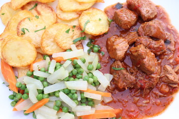 Fleischgericht: Gulasch mit Bratkartoffeln und Gemüse.