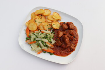 Fleischgericht: Gulasch mit Bratkartoffeln und Gemüse.