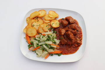 Fleischgericht: Gulasch mit Bratkartoffeln und Gemüse.