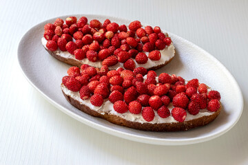 Toast with strawberries and cream cheese. Summer background. Light sandwiches with seasonal berries for breakfast.