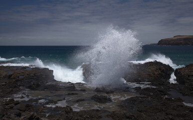 Gran Canaria, north west coast around natural swimming pools Salinas de Agaete, 
waves breaking against old eroded dark lava platform