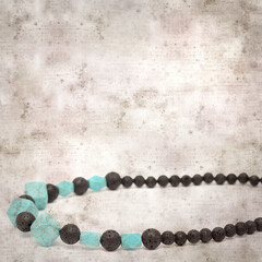 square stylish old textured paper background with necklace made of black volcanic lava beads