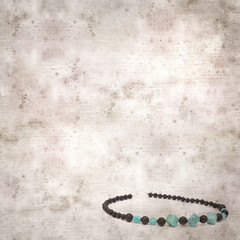 square stylish old textured paper background with necklace made of black volcanic lava beads