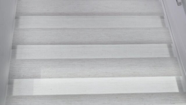 The mechanism of tnaninny roller blinds close up. Duo window roller system day and night. Close up on roller blinds indoors.