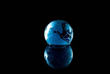 Blue glass planet on a black background.
Globe with reflection in water.