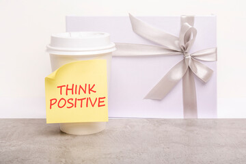 motivational and inspirational quotes on a cup of coffee - THINK POSITIVE. lettering in red on yellow writing paper. white background with space to copy.