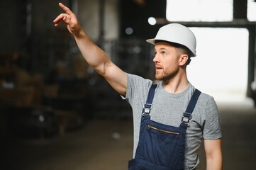 Portrait of happy male worker in warehouse standing between shelves.