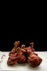 Grilled chicken legs in sauce, on a dark background