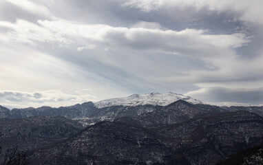 Fototapeta premium Mountains and clouds covered with snow. Mountain peak over the clouds. High mountain landscape.