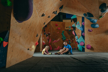 Rock climber father and daughter putting on climbing shoes
