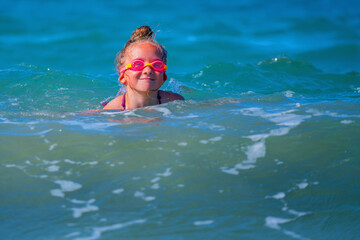 Portrait of happy child girl on breaking wave. Copy space for text or design.