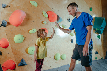 Rock climber father and daughter climbing in a modern gym