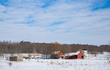 Fototapeta na wymiar Old Amish farm by the woods in winter, snowy farm with red barns | Amish country in Winter | Holmes County, Ohio