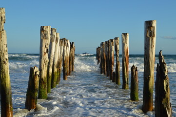 the rests of a wooden pier at the beach
