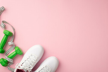 Sports concept. Top view photo of white shoes tape measure and green dumbbells on isolated pastel pink background with empty space
