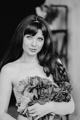 an attractive woman with long hair and bare shoulders and a bouquet of peonies