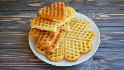 Stack of golden brown Belgian waffles on wooden background.