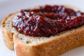 Slice of bread with red fruit jam.