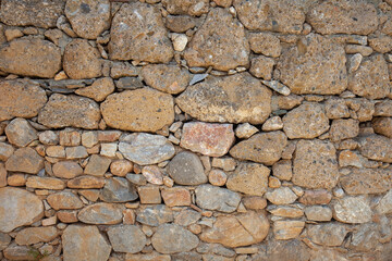
An old stone wall made using different types of stone. Stone wall background. Closeup and front view.
