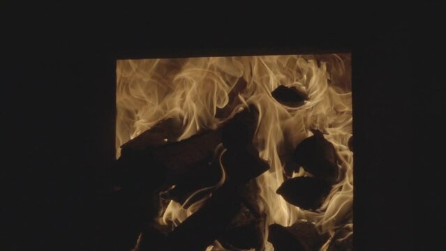 slow motion burning woods in wood fire oven and close up shot of male person throwing wood in oven