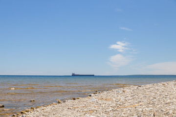 Freighter on the horizon with blue sky and white clouds