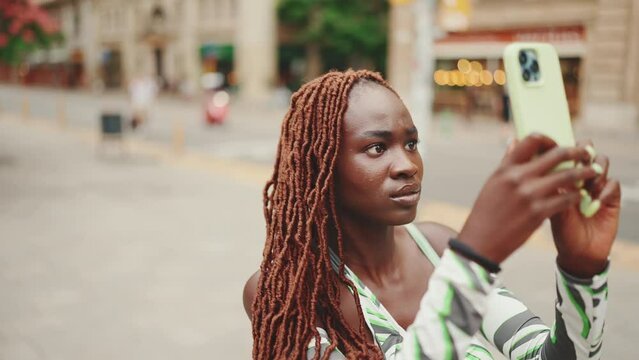 Beautiful woman with African braids takes photo on mobile phone