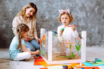 Educator conducting lesson with children in drawing in kindergarten. Kids sitting and painting with...