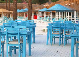 Blue tables and chairs sun loungers and beach umbrellas