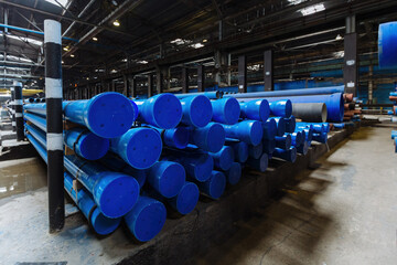 New blue colored cast iron pipes with caps for pipeline construction in warehouse