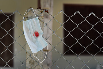 A medical bloodied mask lies on the fence. The concept of coronavirus and the apocalypse resulting...