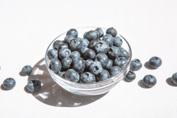 Fresh blue blueberry in bowl and heap of berries on the table, healthy summer food