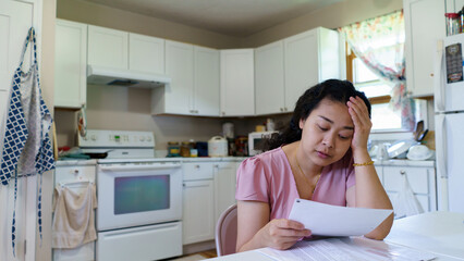 Stressed young asian woman unemployed reading paper pay bills , feeling frustrated of getting...
