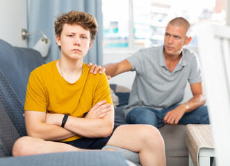 Fototapeta premium Portrait of father calming upset teenage son after quarrel