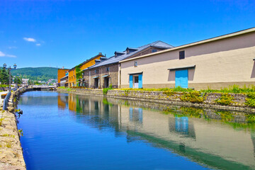 Fototapeta na wymiar 新緑の北海道小樽市、浅草橋街園方面から見る快晴の小樽運河の倉庫群 