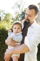 father holding his son in his arms on a background of greenery