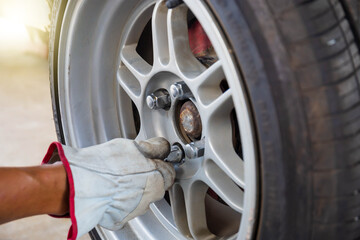 Repair mechanic hands during maintenance work to loosen a wheel nut changing tyre of car