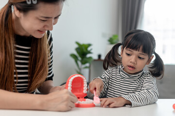 mother teaching daughter child teeth brushing at home