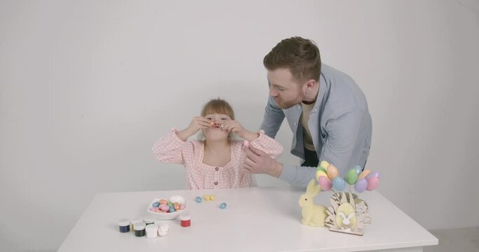 Girl with down syndrome painting Easter eggs with father