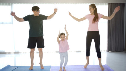 cheerful happy Asian family with father mother and daughter making a home exercise together.