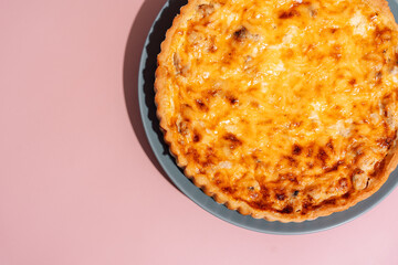 Pie with red fish on a blue plate on a pink background.